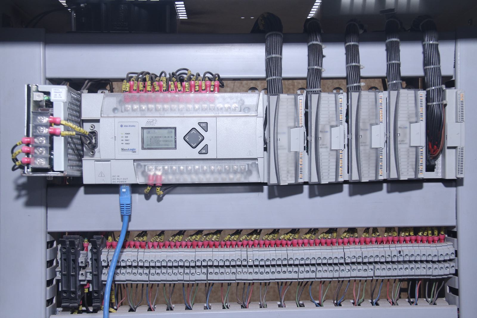 PLC with input cards and Ethernet cable mounted above rows of terminal blocks